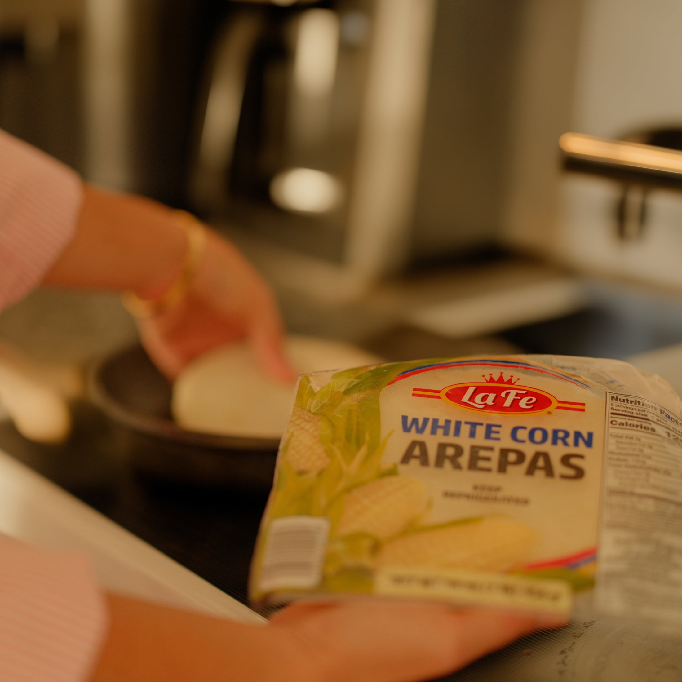 Lafe White Corn Arepas package held above a pan, representing authentic Latin food for delicious meals.