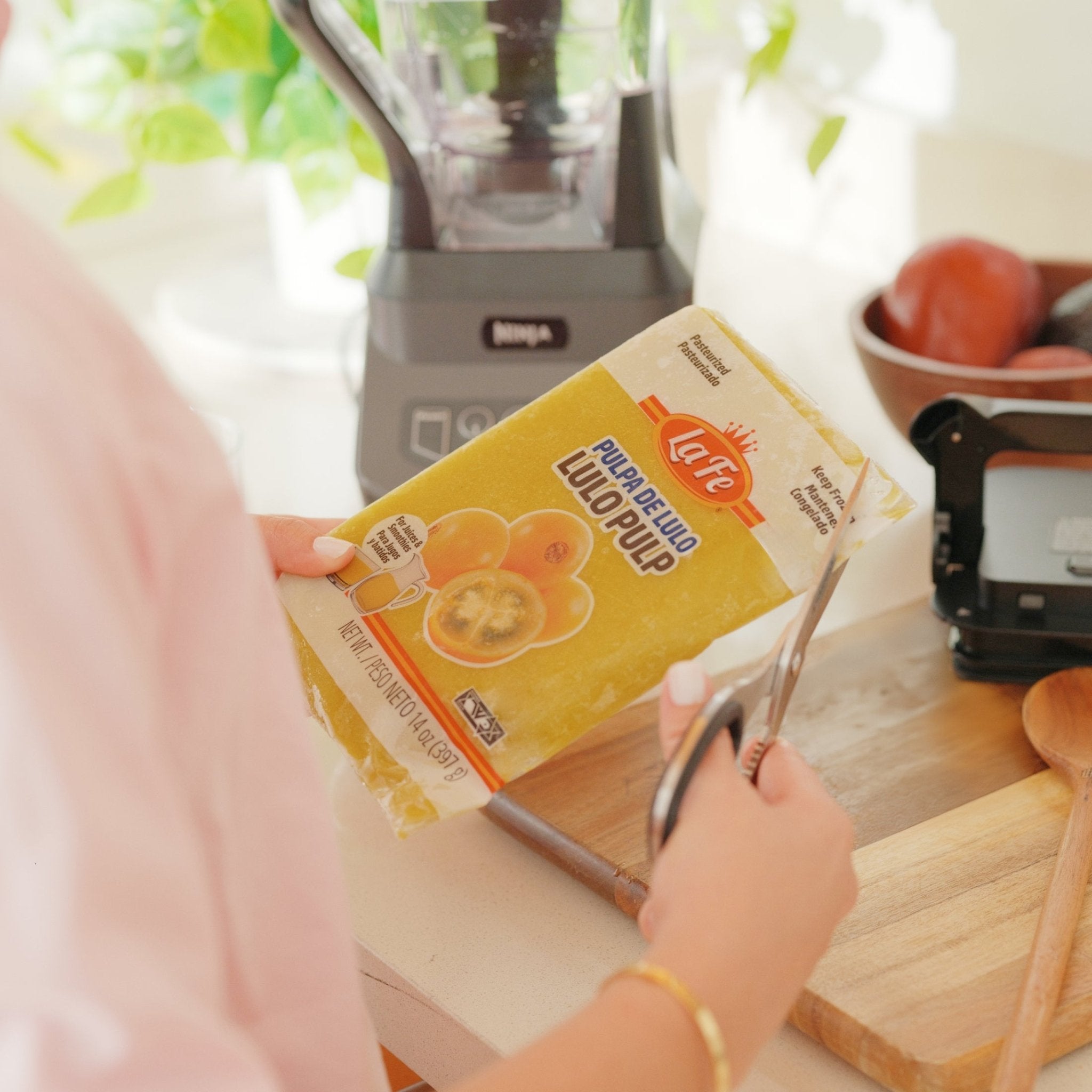 Person cutting open La Fe Pulp Lulo packaging, perfect for authentic Latin food and tropical flavors.