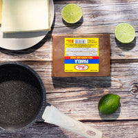 Fela Panela Cuadrada on a wooden countertop with butter and limes, perfect for enhancing authentic Latin flavors in recipes.