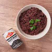 Canned La Fe black beans beside a bowl of delicious, fluffy black rice, a staple in authentic Latin food.