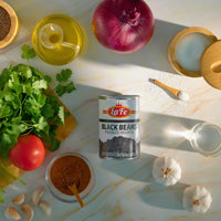 La Fe Black Beans can surrounded by fresh ingredients like cilantro, garlic, tomato, and spices for authentic Latin cooking.