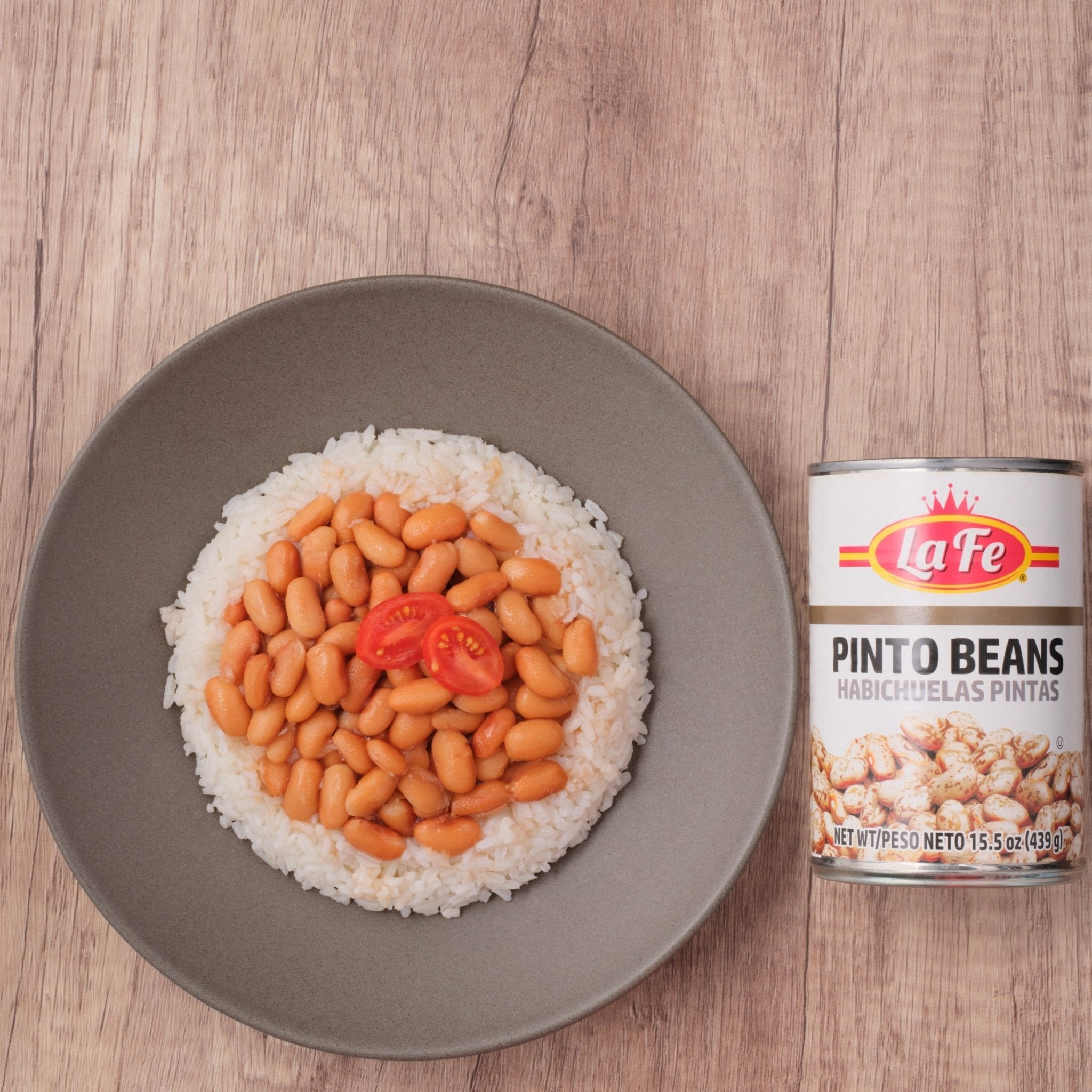 Plate of rice topped with La Fe Pinto Beans and cherry tomatoes, highlighting quality Latin food and flavors.