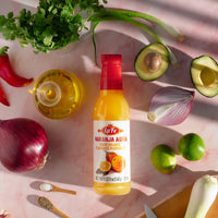 LA FE NARANJA AGRIA bottle with fresh ingredients, perfect for enhancing authentic Latin food flavors.