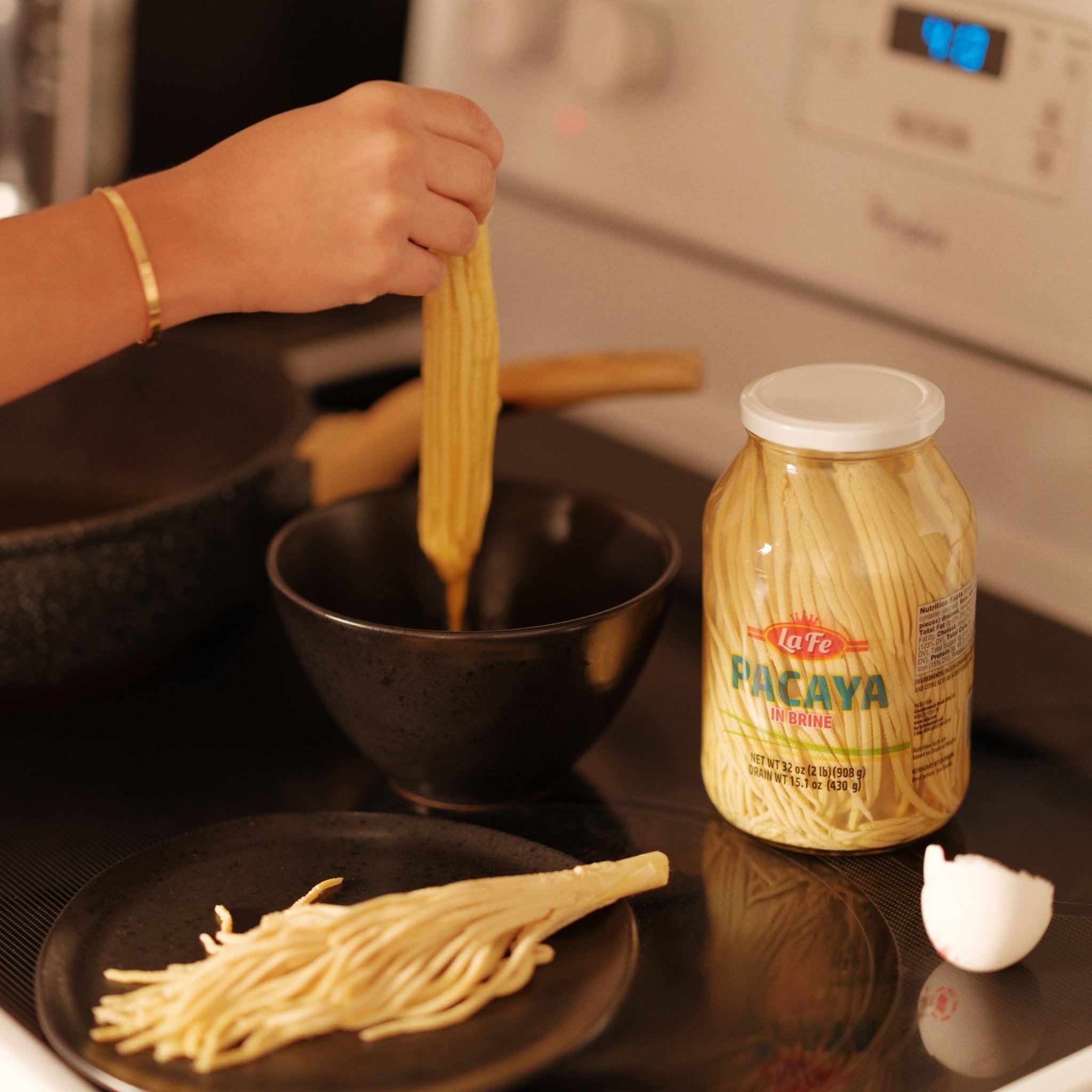 Hand reaching for La Fe Conserva Pacaya in a bowl, showcasing authentic Latin flavors and fresh Latin food.