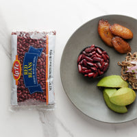 La Fe red beans package next to a plate of Latin food featuring beans, plantains, and fresh avocado.