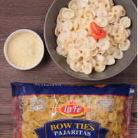 Delicious La Fe bow tie pasta served with creamy sauce, tomato garnish, and grated cheese, perfect for authentic Latin meals.