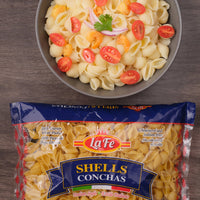 LA FE Pasta Shells in bag with a delicious pasta salad topped with tomatoes and cilantro, perfect for Latin food lovers.
