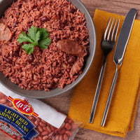 Bowl of red rice with La Fe light red kidney beans, garnished with cilantro, served with fork and knife.