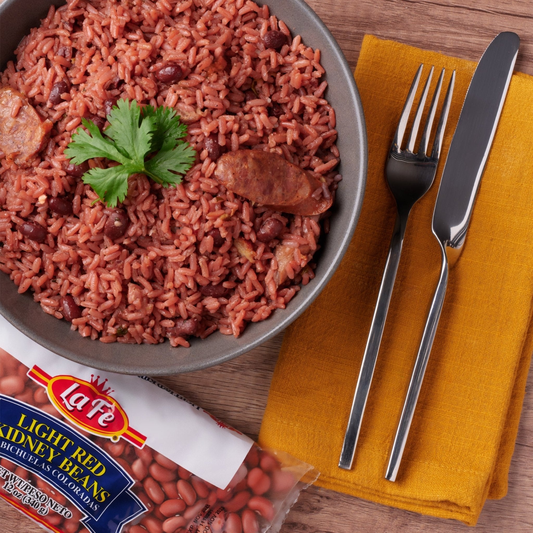 Bowl of red rice with La Fe light red kidney beans, garnished with cilantro, served with fork and knife.
