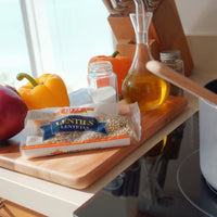 La Fe Dry Lentils on a kitchen counter with fresh vegetables and oil, perfect for authentic Latin food recipes.