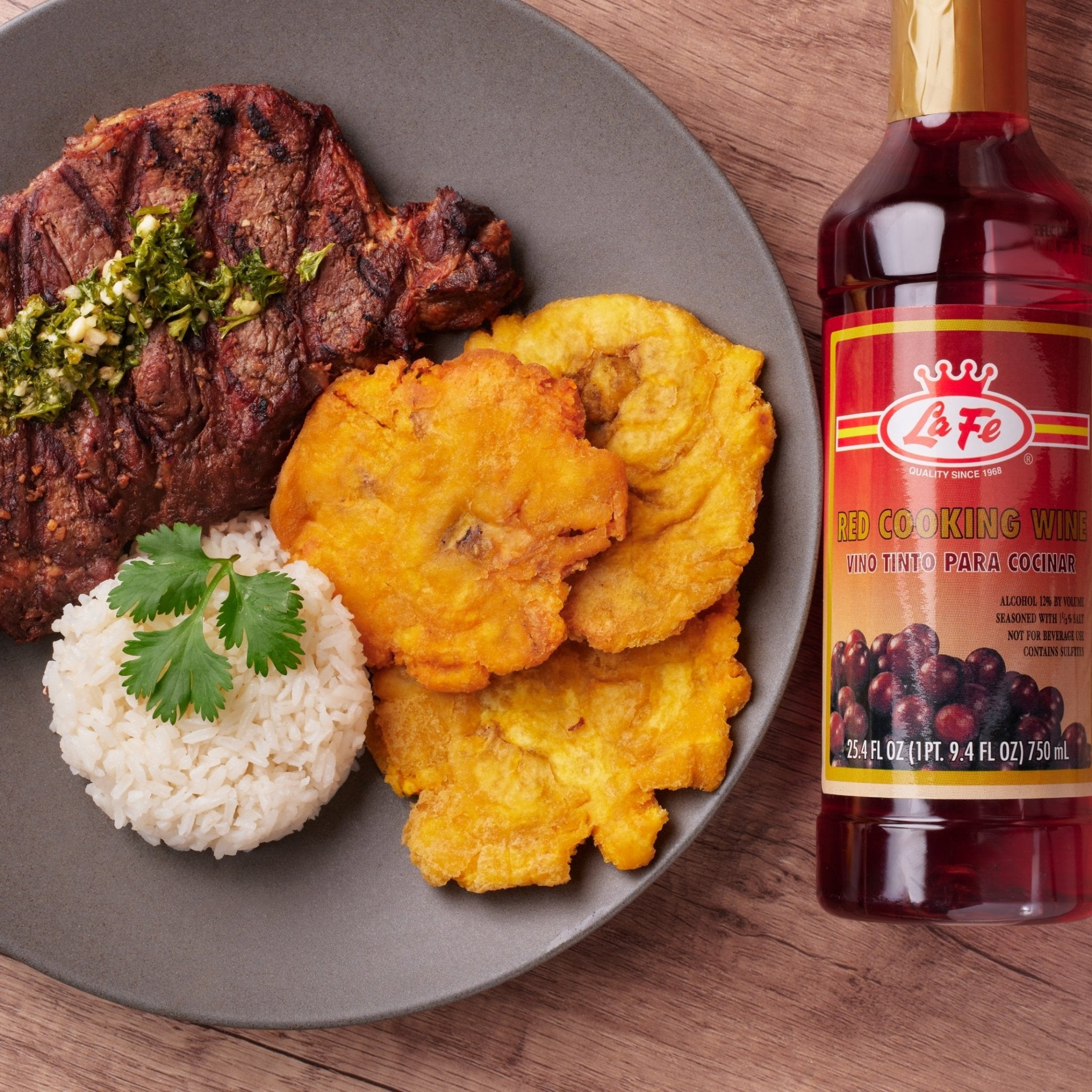 Plate of steak, rice, and tostones with LA FE Red Cooking Wine, showcasing authentic Latin flavors.