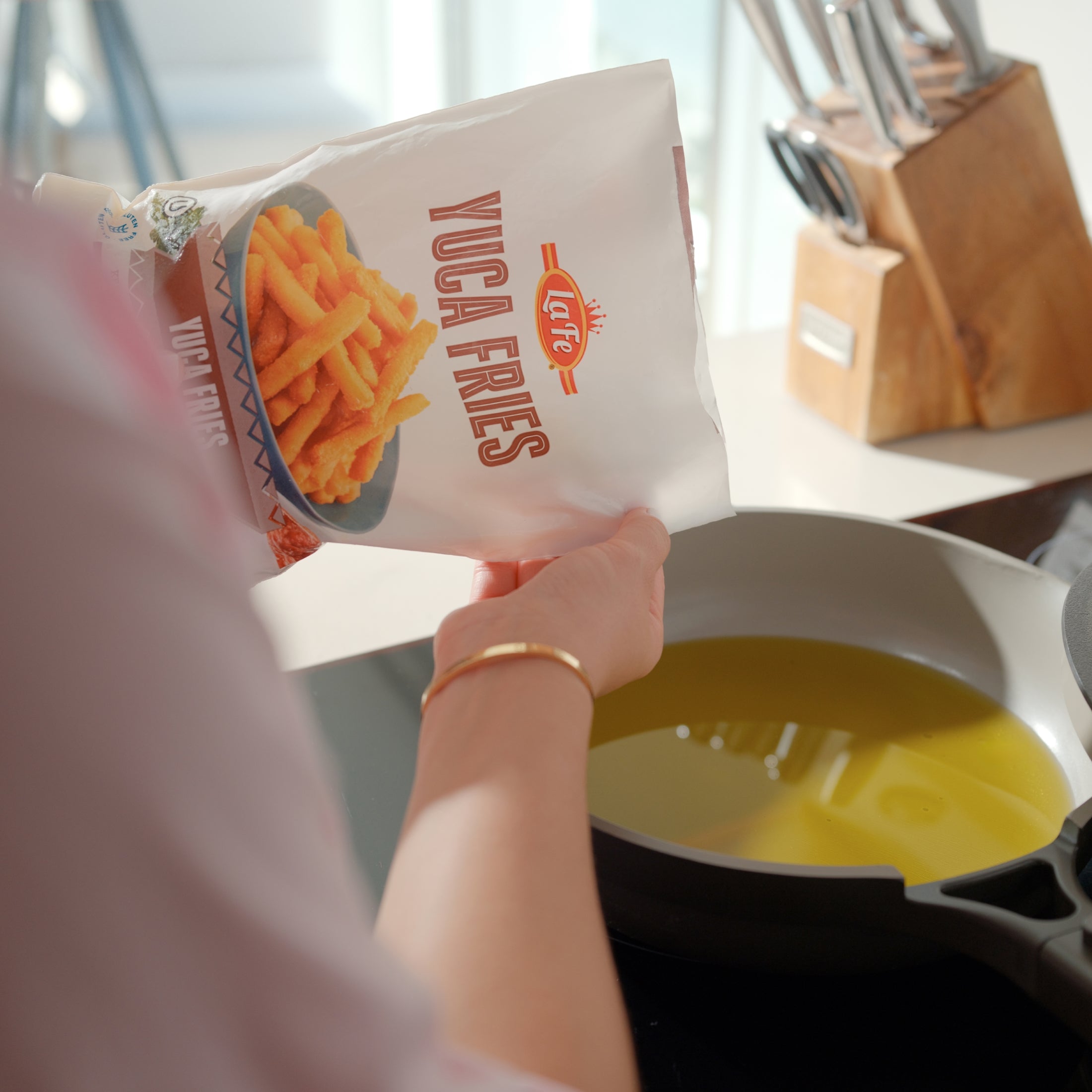Pouring La Fe Yuca Fries into a skillet for a delicious, authentic Latin snack experience.